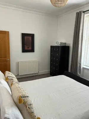 a bedroom with a white bed and a black dresser at 1L Albert Place Maddiston Road Brightons Falkirk FK2 0JX in Polmont