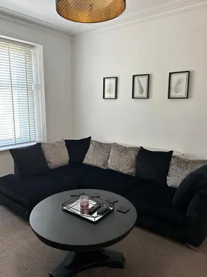 a living room with a black couch and a table at 1L Albert Place Maddiston Road Brightons Falkirk FK2 0JX in Polmont