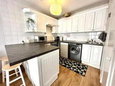 a kitchen with white cabinets and a washer and dryer at City Centre Hidden Hideout for 2 in Edinburgh
