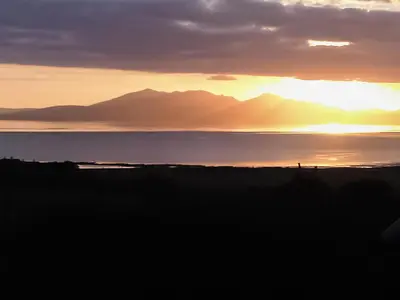 a sunset over the water with mountains in the background at Sorbie Villa in Stevenston