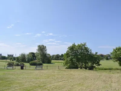 a park with benches and trees in a field at Sorbie Villa in Stevenston