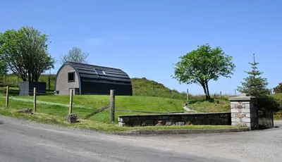 a barn on a hill next to a road at Macree Pod in Taynuilt