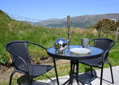 a table with a tea kettle and chairs on a patio at Macree Pod in Taynuilt