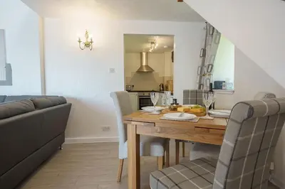 a dining room and kitchen with a table and chairs at Jane Welsh Cottage in Thornhill