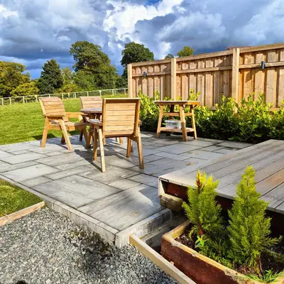 a wooden patio with two chairs and a table at Devonknowes lodges in Tillicoultry