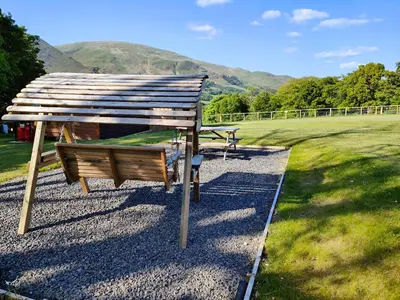 a wooden picnic table and bench in a field at Devonknowes lodges in Tillicoultry