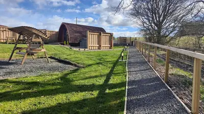 a wooden barn with a fence and a wooden bench at Devonknowes lodges in Tillicoultry