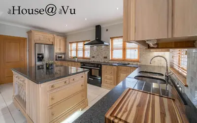 a large kitchen with wooden cabinets and a sink at The Hoose at The Vu in Bathgate