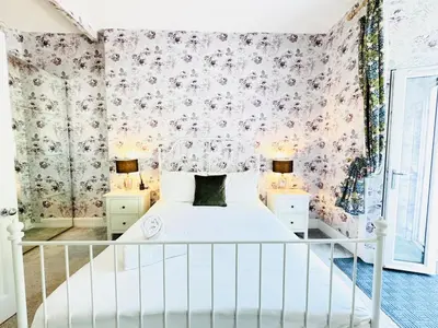 a bedroom with a white bed and floral wallpaper at City Centre Escape with Private Garden in Edinburgh