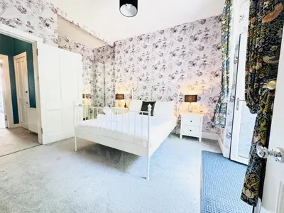 a bedroom with a white bed and pink floral wallpaper at City Centre Escape with Private Garden in Edinburgh