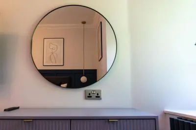 a mirror on a wall above a vanity in a bathroom at Oban Apartments in Oban