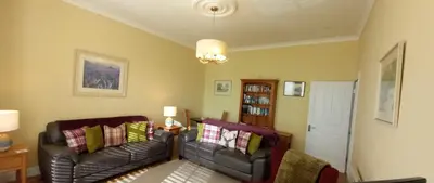 a living room with two leather couches and a table at Stunning Village Centre Holiday Home in Callander