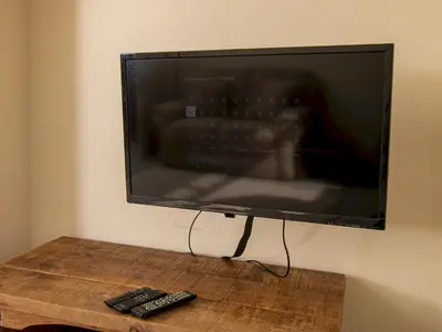 a flat screen tv hanging on a wall with two remote controls at Private Entrance GF 2 bed flat near Renfrew Centre - Pass the Keys in Renfrew