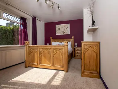 a bedroom with a wooden bed and a window at Private Entrance GF 2 bed flat near Renfrew Centre - Pass the Keys in Renfrew