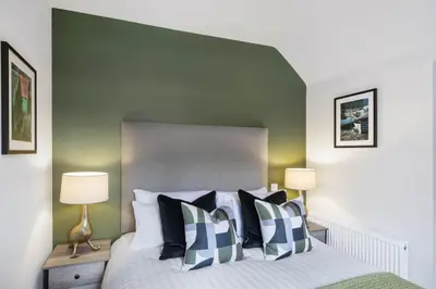 a bedroom with a bed with a green headboard at The Woodside Apartments in Doune