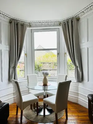 a dining room with a table and chairs and a window at THE LAZY LION - Spacious 2 Bedroom - Town Centre Holiday Home Apartment in Port Glasgow