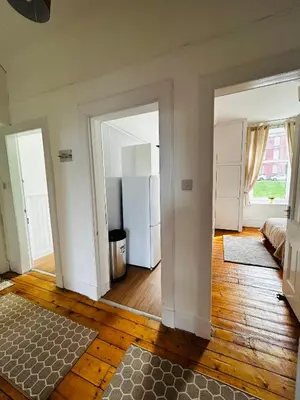 a living room with a refrigerator and wooden floors at THE LAZY LION - Spacious 2 Bedroom - Town Centre Holiday Home Apartment in Port Glasgow