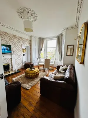 a living room with a couch and a table at THE LAZY LION - Spacious 2 Bedroom - Town Centre Holiday Home Apartment in Port Glasgow