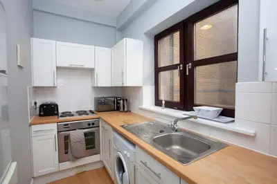 a kitchen with white cabinets and a sink and a window at Modern and refurbished Flat in Merchant City in Glasgow