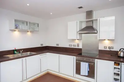 a kitchen with white cabinets and stainless steel appliances at Fantastic City Centre Flat in Glasgow