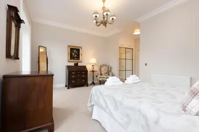 a bedroom with a large white bed and a dresser at Deluxe 3-bedroom Apartment on Princes Street overlooking Edinburgh Castle in Edinburgh
