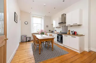 a kitchen with a wooden table and a kitchen with white cabinets at Tasteful 1-bedroom Apartment near Edinburgh Meadows in Edinburgh
