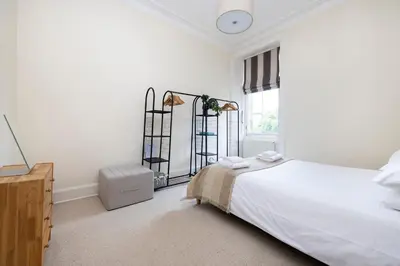 a white bedroom with a bed and a window at Tasteful 1-bedroom Apartment near Edinburgh Meadows in Edinburgh