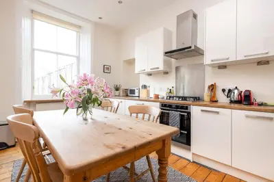 a kitchen with a wooden table with pink flowers on it at Tasteful 1-bedroom Apartment near Edinburgh Meadows in Edinburgh