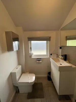 a bathroom with a toilet and a sink and a window at The Mail Barn Studio in Lamlash