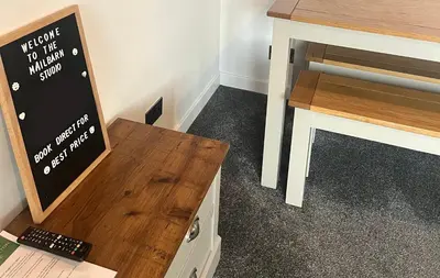 a desk with a sign next to a wooden table at The Mail Barn Studio in Lamlash
