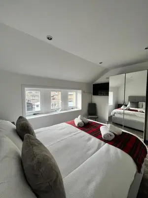 a large white bedroom with a large bed with pillows at Very Central, Charlotte Square, near the Castle in Edinburgh