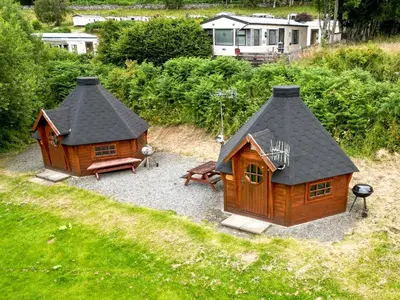 a small house with a roof and a bench at Cruachan Caravan and Camping Farm in Killin