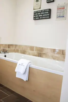 a bathroom with a white towel on the side of a tub at Pear Tree Cottage in Limekilns