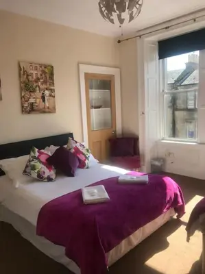 a bedroom with a large bed with purple blankets at Central 3 bedrooms apartment for upto 6 in Edinburgh