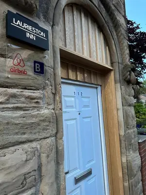 a door on a stone building with a sign above it at Laurieston Penthouse in Grahamston