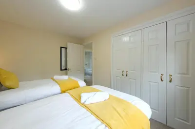 two beds in a bedroom with white walls and yellow blankets at Pure Apartments Commuter- Dunfermline South in Fife
