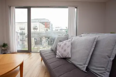 a couch in a living room with a large window at 1 Bedroom Flat in the Heart of Merchant City in Glasgow