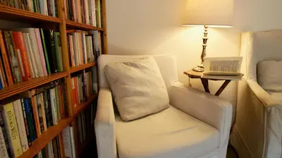 a white chair sitting next to a book shelf at Glen Cottage in Comrie