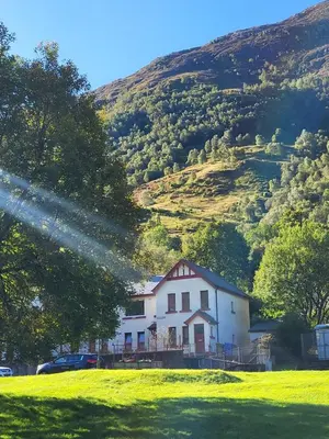 a white house with a hill in the background at Kinlochleven Holiday Home in Kinlochleven