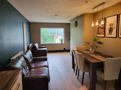 a living room with a table and a leather couch at Kinlochleven Holiday Home in Kinlochleven