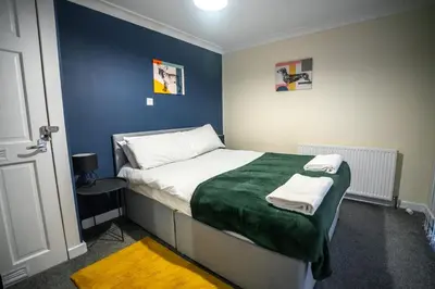 a bedroom with a bed with a green blanket at Livi House in Livingston