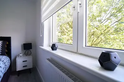 a bedroom with a window with two vases on a window sill at Woodside Apartment in Coatbridge
