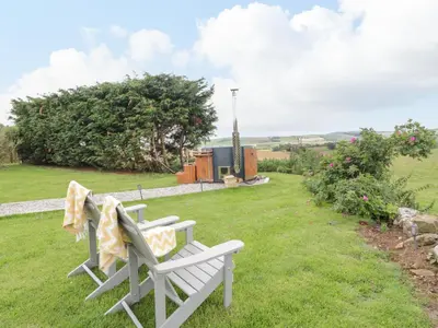 two white benches sitting on the grass in a yard at Greenacres Carriage in Maybole