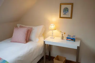 a bedroom with a bed and a table with a lamp at Kennels Cottage in Killin