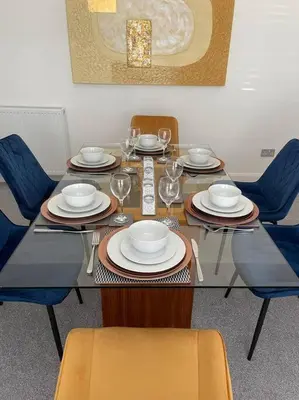 a dining table with chairs and plates and wine glasses at Fantastic home in Brightons, Falkirk. in Polmont