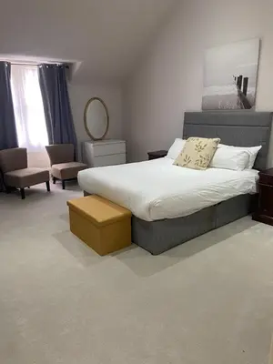 a bedroom with a large bed and a chair at Merchiston Residence in Edinburgh