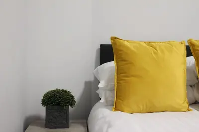 a yellow pillow and a potted plant on a bed at The Arches The Wee Yin in Stirling