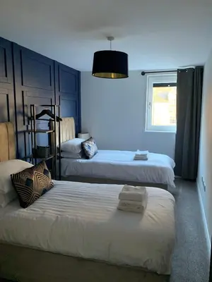 a bedroom with two beds with blue walls and a window at Hillview in Oban