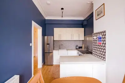 a kitchen with blue walls and a refrigerator at JOIVY Splendid Apartment near Haymarket in Edinburgh