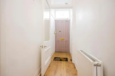 a hallway with a pink door and a wooden floor at JOIVY Splendid Apartment near Haymarket in Edinburgh